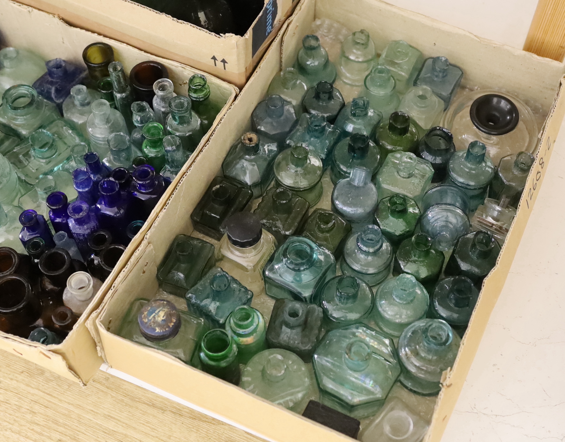 A collection of late 19th/early 20th century glass ink bottles, drink bottles and sauce bottles, brand names and advertising moulded into the glass on a number of examples, many ink bottles with pen rests moulded into th